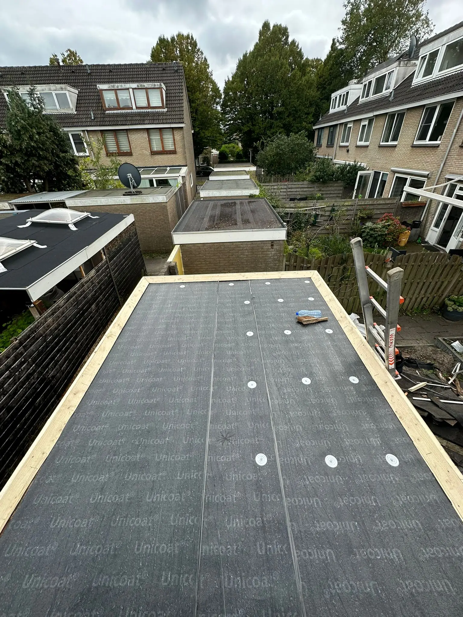 Professionele dakdekker brengt waterdichte bitumen dakbedekking aan op plat dak